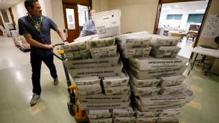 Chet Harhut, deputy manager, of the Allegheny County Division of Elections, wheels a dolly loaded with mail-in ballots, at the division of elections offices in downtown Pittsburgh Wednesday, May 27, 2020. The once-delayed June 2, Pennsylvania primary will feature legislative and congressional races, a first run for some new paper-record voting systems and the inaugural use of newly legalized mail-in ballots.