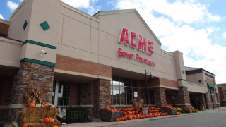 A storefront reads "ACME Savon Pharmacy." At the entrance sit various pumpkins.