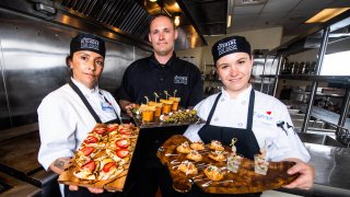 Integrantes de Kitchen for Goog sostiene bandejas de comida
