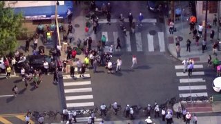 aerial image of crowd gathered outside police station. some in crowd have baseball bats