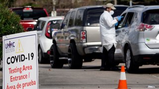 A healthcare worker processes people waiting in line at a United Memorial Medical Center COVID-19 testing site Thursday, Nov. 19, 2020, in Houston. Texas is rushing thousands of additional medical staff to overworked hospitals as the number of hospitalized COVID-19 patients increases.