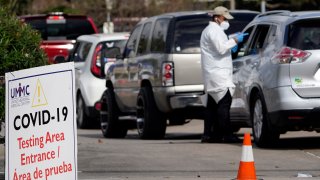 A healthcare worker processes people waiting in line at a United Memorial Medical Center COVID-19 testing site Thursday, Nov. 19, 2020, in Houston. Texas is rushing thousands of additional medical staff to overworked hospitals as the number of hospitalized COVID-19 patients increases.