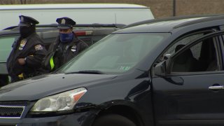 Two Philadelphia police officers stand next to a black van that has its front driver's side door open