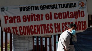Hombre camina frente un aviso de alerta de contagio en Ciudad de México