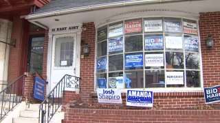 Multiple campaign signs and posters, including some supporting President Joe Biden and Vice President Kamala Harris, adorn the front window of the Montgomery County Democratic Committee's Norristown office.