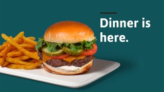 Fries and Burger for sale at Wawa on a plate against a green background with the phrase "Dinner Is Here"