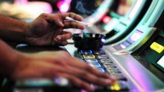 Closeup of a person smoking a cigarette at a casino machine