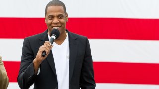 Jay-Z smiles in front of a large American flag
