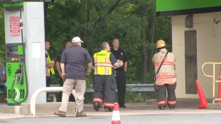 Hazardous material workers walk around a gas station in Delaware County after gasoline spilled into nearby waterways.