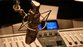 Radio station microphone in front of mixing board.