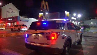 Crime scene tape runs across the back of a Philadelphia police SUV that is parked in front of a McDonald's.