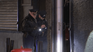 Two Philadelphia police officers point their flashlights at a door handle