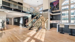 A glass staircase next to a kitchen and statues.