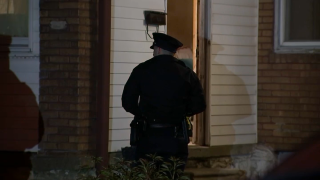 A police officer stands in front of the front door of a home.