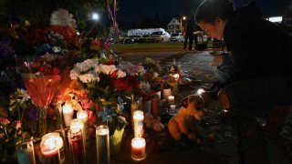 La gente enciende velas en un monumento improvisado cerca de una tienda Tops Grocery en Buffalo, Nueva York, el 15 de mayo de 2022, el día después de que un hombre armado matara a tiros a 10 personas.