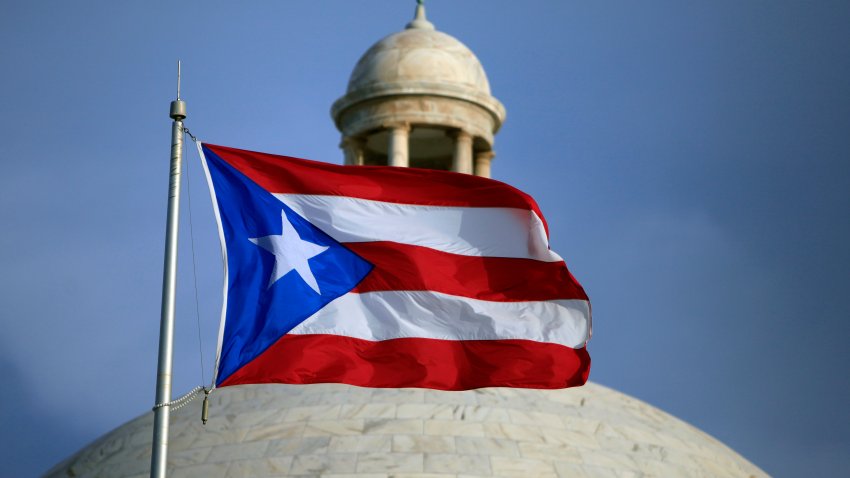 FILE –  The Puerto Rican flag flies in front of Puerto Rico’s Capitol as in San Juan, Puerto Rico, July 29, 2015. A group of Democratic congress members, including the House majority leader, on Thursday, May 19, 2022, proposed a binding plebiscite to decide whether Puerto Rico should become a state or gain some sort of independence.