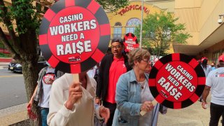 Casino workers outside a casino hold up chip signs demanding better wages