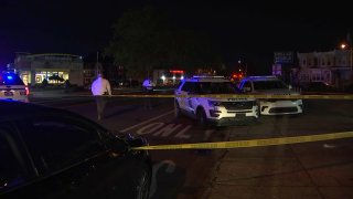 Police SUVs parked on a street behind crime scene tape.