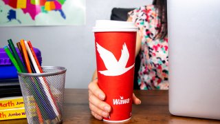 Woman holds a red Wawa coffee cup on a desk