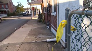 A piece of crime scene tape hangs from a fence