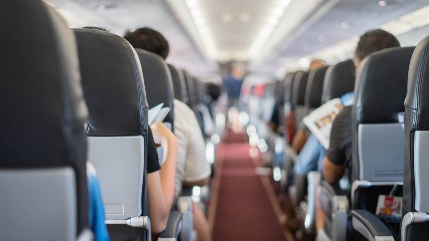 passenger seat, Interior of airplane with passengers sitting on seats and stewardess walking the aisle in background. Travel concept,vintage color