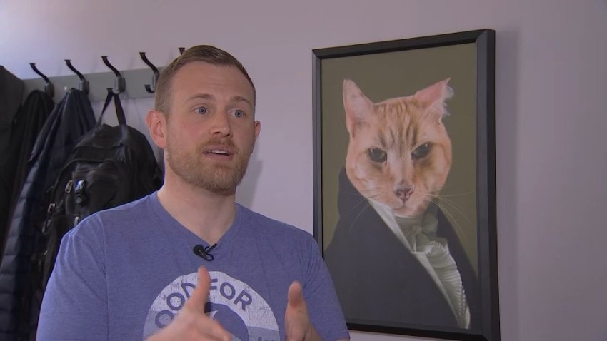 Josh Kruger, with a portrait of his cat Russ, in an interview with NBC10 in 2019.