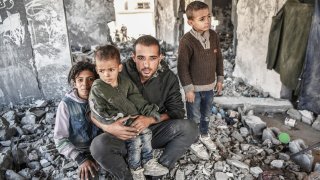 Mahmoud Abu Dorra junto a sus cuatro hijos, en lo que quedó de su casa en Rafah, Gaza, tras una ataque de Israel, donde murió su esposa hace unos días.