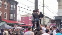 People attempt to climb the greased pole at the 2024 South 9th Street Italian Market festival in Philadelphia.