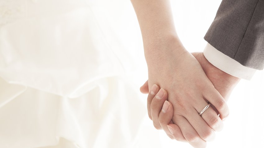 Young married couple holding hands, ceremony wedding day