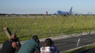 La gente toma fotos mientras el Air Force One llega a la RAF Mildenhall, cerca de Bury St Edmunds, en el este de Inglaterra, el miércoles 9 de junio de 2021.