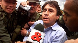 Fabio Ochoa Vásquez (centro) es escoltado por la policía a su llegada a Bogotá el 13 de octubre de 1999, poco después de ser capturado junto con otros 29 narcotraficantes por las autoridades colombianas como parte de una operación encubierta internacional masiva llamada en código "Operación Milenio" en la que participaron los Estados Unidos, México y Ecuador.