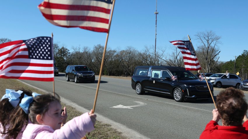 PLAINS, GEORGIA – JANUARY 04: Mourners line the street and wave flags as former U.S. President Jimmy Carter’s hearse passes by on January 04, 2025 in Plains, Georgia. Six days of funeral observances will take place for former President Jimmy Carter after he died on Dec. 29 at the age of 100. President Carter was the longest-living U.S. President in history. He was known as much for his long post-presidency and continued life of service as he was for his one term in office. He was pivotal in negotiating the Camp David Accords and earned the Nobel Peace Prize in 2002. (Photo by Joe Raedle/Getty Images)