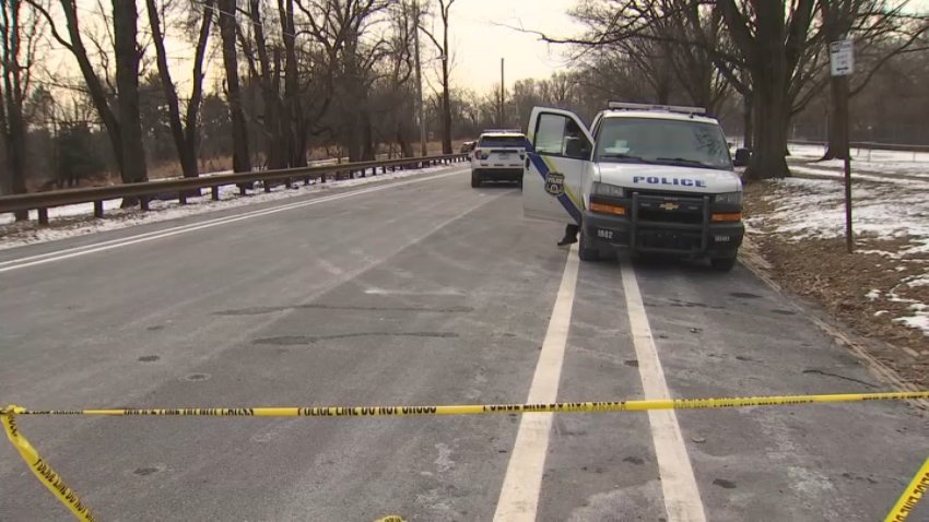 Yellow police tape blocks off road with Philadelphia Police Department van parked behind it