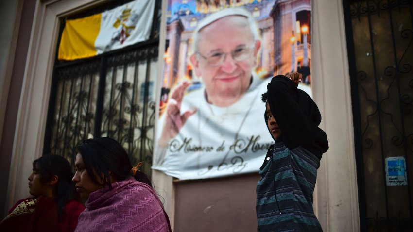 La gente de pie en una calle de San Cristóbal de las Casas, estado de Chiapas, el 14 de febrero de 2014, con un retrato en el fondo del papa Francisco, en la víspera de su llegada para una misa al aire libre.